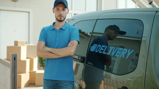 Porträt eines Zustellers, der in der Nähe eines Lieferwagens steht, im Hintergrund Kartons — Stockvideo