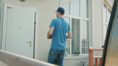 Teslimat işçisi, erkek müşterilere paket getiriyor. Dışarıda duran kutuyu veriyor.