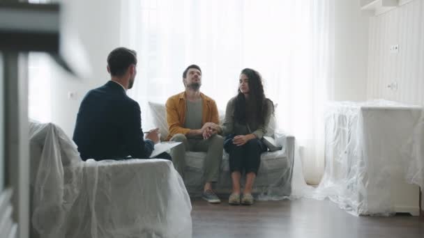 Man en vrouw op zoek naar nieuw huis en praten met makelaar binnen in gezellige kamer — Stockvideo