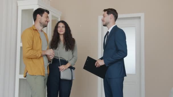 Man taking keys from realtor shaking hands hugging happy wife smiling laughing — Stock Video