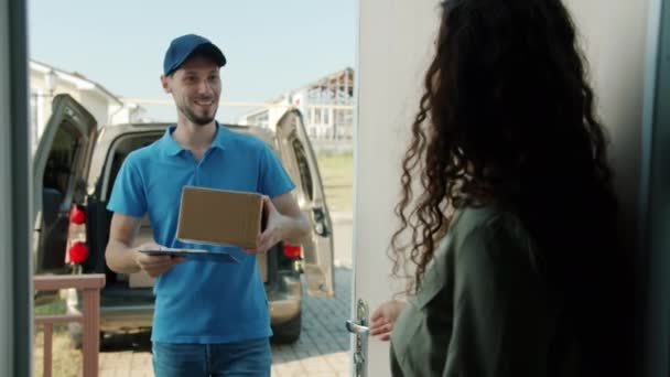 Mooi meisje opening huis deur nemen pakket van postbode ondertekening papier praten — Stockvideo