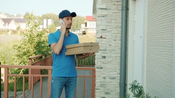 Repartidor de pizza hombre hablando en el teléfono móvil y luego dando cajas a la mujer feliz cliente — Vídeos de Stock