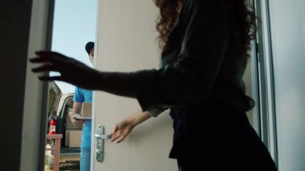 Повільний рух жінки, що відкриває вхідні двері, бере посилку від паперу, що підписує чоловіка — стокове відео