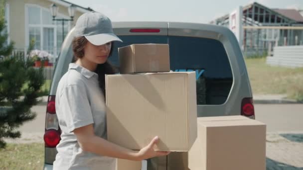 Jovem mulher de uniforme transportando caixas de entrega van para casa trabalhando sozinha — Vídeo de Stock