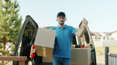 Minibüsten eve kutular taşıyarak ve kulaklıkla müzik dinleyerek eğlenerek.