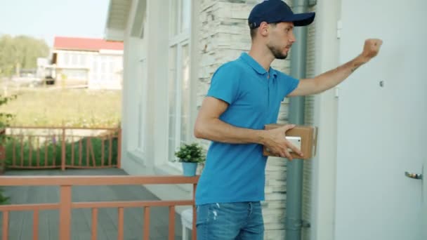 Deliveryman δίνοντας πακέτο σε νεαρή κοπέλα, στη συνέχεια, χρησιμοποιώντας smartphone οθόνη αφής σε εξωτερικούς χώρους — Αρχείο Βίντεο