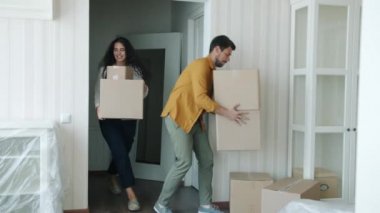 Neşeli çift yeni eve karton kutular taşıyorlar. Sarılmışlar etrafa bakınıyorlar.