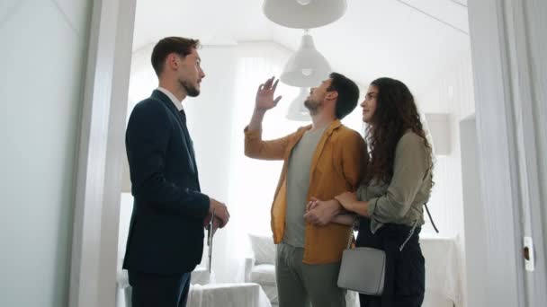 Flicka och kille köper lägenhet skakar hand med mäklare kramas diskutera kontrakt — Stockvideo