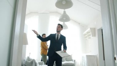 Emlakçı müşterilere evi gösteriyor. Konuşuyorlar, sonra el sıkışıyorlar.