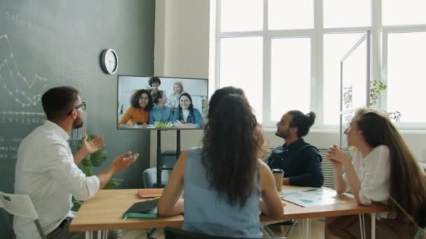 Diverso grupo de empresarios charlando con colegas mujeres a través de videollamadas mirando a la pantalla en la oficina — Vídeos de Stock