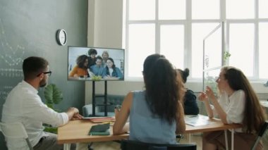 Ofisteki dijital ekranı kullanarak video görüşmeleri yapan çok ırklı bir iş grubu