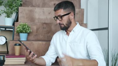 Ofisteki tabletle konuşan ve el kol hareketi yapan yakışıklı iş adamı.