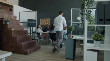 Şen şakrak işadamı ofiste scooter sürüyor sonra beşlik çakıyor ve ofiste el çırpıyor.