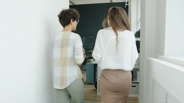 Sembrar el movimiento de la empleada femenina caminando en la oficina hablando con su compañero de trabajo y luego viendo la presentación de la pantalla digital — Vídeo de stock