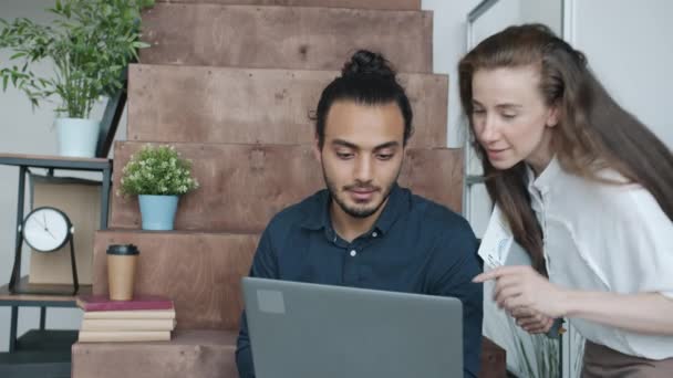Männliche und weibliche Kollegen im multiethnischen Team unterhalten sich im gemeinsamen Büro am Laptop. Kommunikations- und Personenkonzept. — Stockvideo