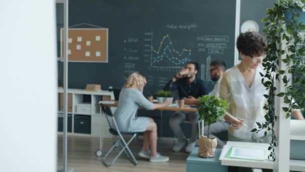 Zoom-in biznesmenów pracujących w biurze spacerujących z papierami i rozmawiających przy stole — Wideo stockowe