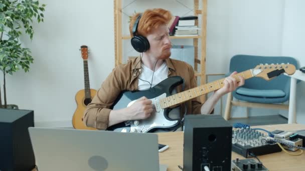 Портрет радостного парня-музыканта, играющего на электрогитаре и развлекающегося дома — стоковое видео