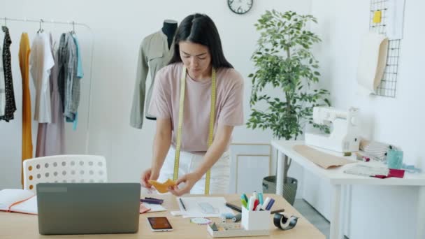 Långsam rörelse av ung asiatisk kvinna kläder designer välja material och färg för nya plagg — Stockvideo