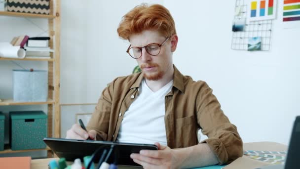 自宅で屋内で起草タブレットコンピュータの図面で作業若い男のデザイナーの肖像画 — ストック動画