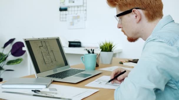 Ambiciózní architekt kontrolující stavební plán při pohledu na obrazovku notebooku pracující v kanceláři sám — Stock video