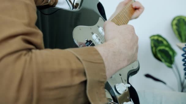 Крупный план рук гитаристов, играющих на электроинструменте, касающихся струн в помещении студии — стоковое видео