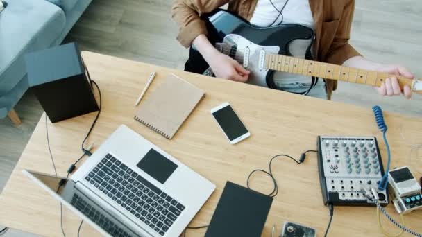 Homem irreconhecível tocando guitarra elétrica na mesa com equipamento moderno laptop e misturador de som — Vídeo de Stock