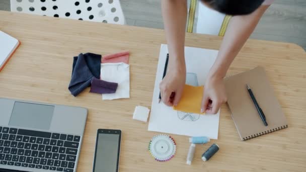 Primo piano della sarta donna che sceglie il colore tessile per i nuovi vestiti che lavorano alla scrivania in officina — Video Stock