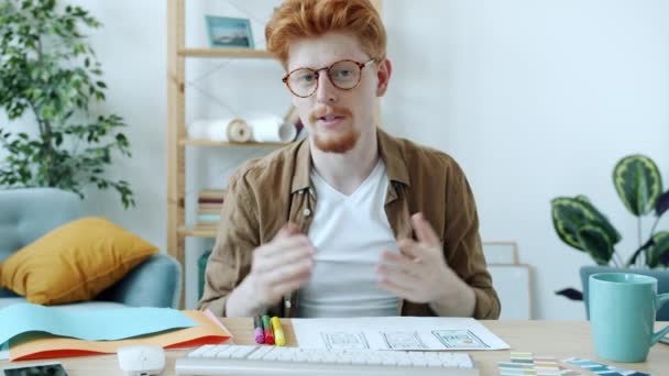 Fiatal férfi tervező, hogy online video hívást számítógépes fényképezőgép beszél, és bemutatja okostelefon képernyő képek — Stock videók