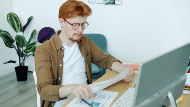 Joven masculino profesional de diseño de aplicaciones móviles interfaz mirando fotos y mecanografía con el ordenador en la oficina — Vídeo de stock