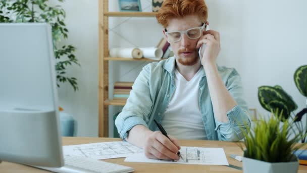남자 건축가가 휴대폰으로 얘기하는 모습 과 아파트 책상에 앉아 있는 건설 계획에서 일하는 모습 — 비디오