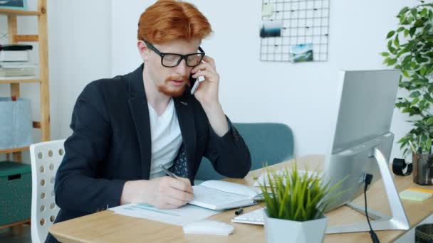 Porträt eines erfolgreichen Büroangestellten, der mit dem Handy spricht und allein mit dem Computer arbeitet — Stockvideo