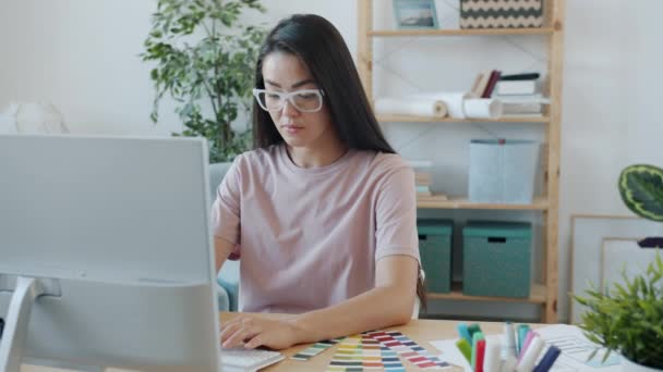 아시아의 진지 한 여성 창의적 디자이너가 컴퓨터 타이핑을 하며 컬러 팔레트를 보는 모습 — 비디오