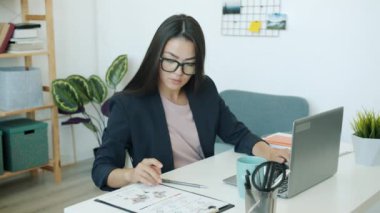 Bilgisayarla çalışan Asyalı güzel bayanın yavaş çekimde kapalı alandaki işe odaklanması.