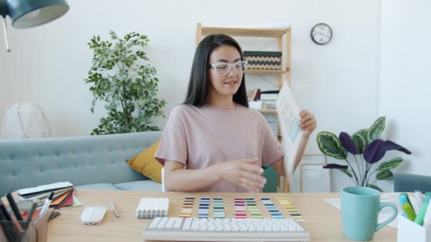 Joven diseñadora alegre hablando de colores para aplicaciones móviles durante la videollamada en línea en casa — Vídeo de stock