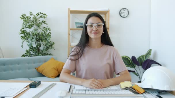 Joven mujer asiática arquitecta charlando mirando a la cámara durante la videollamada en línea desde casa — Vídeo de stock