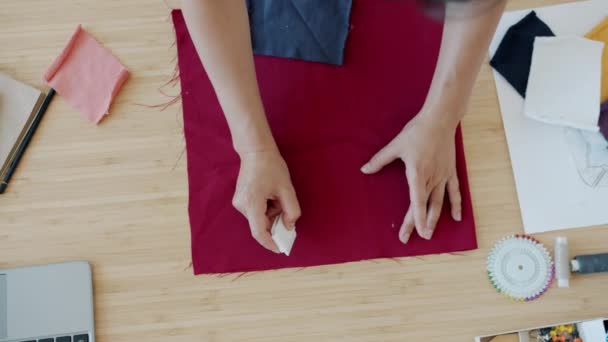 Primer plano de las manos femeninas dibujo sobre el material con tiza bosquejo prenda hecha a mano en la mesa — Vídeos de Stock