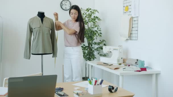 Slow motion van Aziatische vrouw naaister meten kledingstuk op kleermakers dummy het creëren van handgemaakte kleding. — Stockvideo