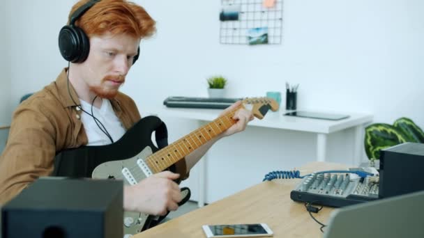 Movimento lento de músico ambicioso tocando guitarra elétrica e usando computador em casa — Vídeo de Stock