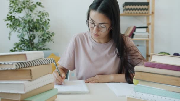 Zpomalený pohyb pilného studenta psaní eseje sedí za stolem s knihami doma — Stock video
