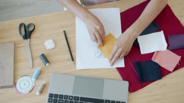 Modern moda tasarımcılarının yüksek açılı görüntüsü elleri masadaki bilgisayarları ve farbiği seçiyor.