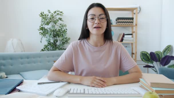 Krásná asijské dívka student mluvení a gestikulace během on-line videohovor v bytě — Stock video
