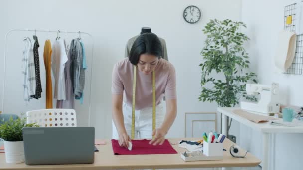 Cámara lenta de mujer asiática costurera trabajando con tela y tiza creando nueva prenda moderna — Vídeos de Stock