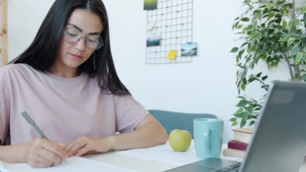 Slow motion van mooie Aziatische vrouw student leren thuis schrijven en kijken naar laptop scherm — Stockvideo