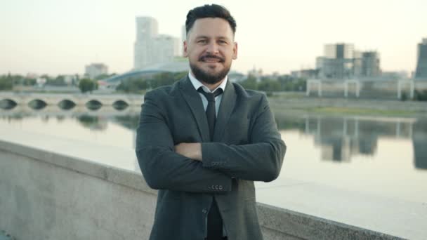 Retrato en cámara lenta del ambicioso hombre de negocios parado al aire libre en el terraplén de la ciudad moderna — Vídeos de Stock