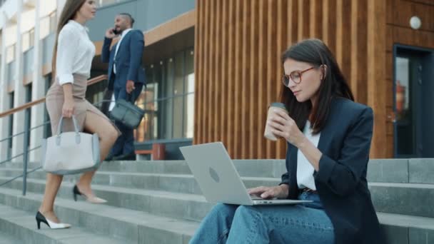 Retrato de alegre empresaria trabajando con laptop y disfrutando de ir a tomar un café en las escaleras del edificio de oficinas — Vídeos de Stock