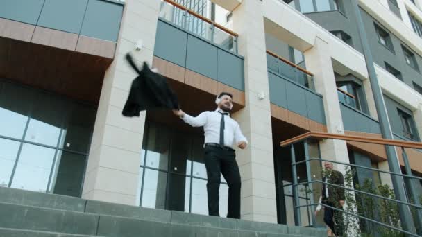 Loco hombre de negocios bailando al aire libre cerca del edificio de oficinas escuchando música a través de auriculares — Vídeos de Stock