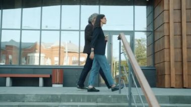 Güzel genç iş kadını, modern bina inşaatında iş arkadaşlarını karşılamaya gidiyor.