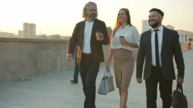 Bir grup iş adamı sıcak bir yaz gününde dışarıda konuşup gülümsüyor.