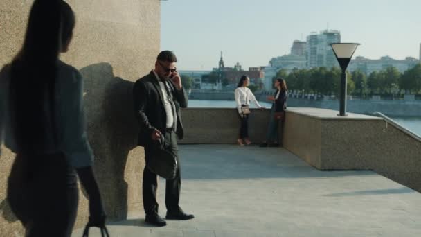 Portret mężczyzny w garniturze rozmawiającego przez telefon komórkowy stojący przy biurowcu w nasypie — Wideo stockowe