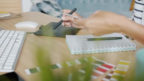 Kadın elinin, evdeki bilgisayar masasında çalışan grafik tableti kullanarak yakın plan görüntüsü — Stok video